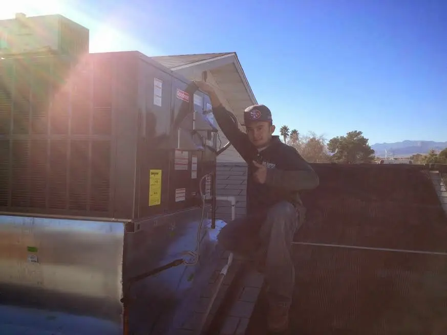 HVAC technician performing Air Duct Cleaning on a rooftop unit in Redlands